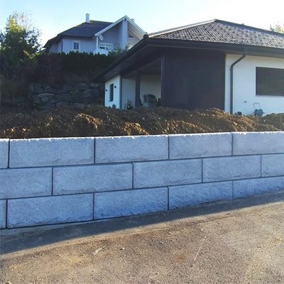 Strukturierte Stützwand als moderne Grundstücksgrenze – die versiegelte Oberfläche schützt dauerhaft
