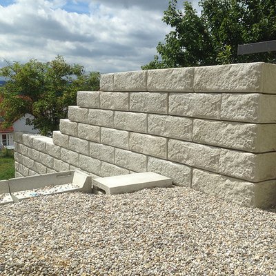 Gerade Betonmauer schafft Sichtschutz und stabilisiert die erhöhte Terrasse elegant