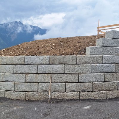 Sichere Hangabstützung mit Mauer aus strukturierten Betonsteinen am Straßenrand