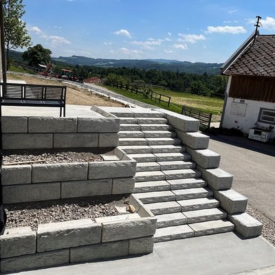 Hanglösung mit Treppenaufgang – kombiniert Betonstufen mit strukturierter Stützmauer