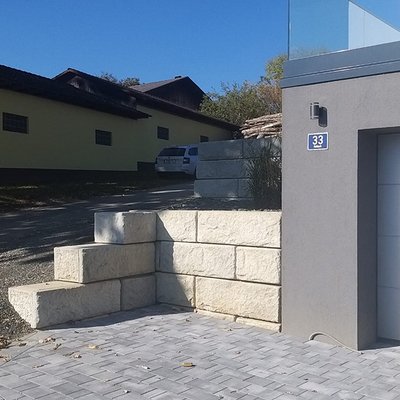 Die erhöhte Stützwand grenzt die Garagenzufahrt stilvoll vom Hang ab – modern und massiv