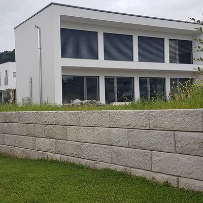 Strukturierte Betonsteine bilden eine elegante Mauer – passend zur klaren Hausarchitektur