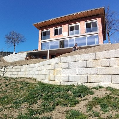 In Hanglage errichtete Betonmauer schafft ebene Flächen rund ums Neubauhaus