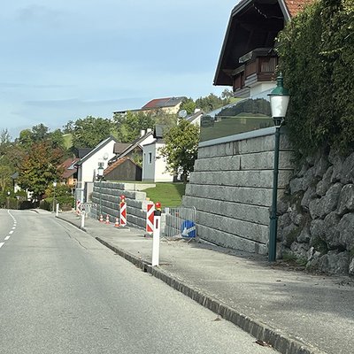 Hohe Stützmauer aus Betonblöcken entlang einer Straße zur Abstützung und Gartenerweiterung in Ertl