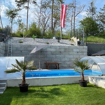 Hohe Betonmauer sichert den Hang hinter dem Pool und schafft mehr nutzbaren Gartenplatz