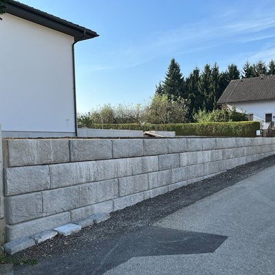 Hohe Stützmauer aus Betonsteinen als stabile Grundstücksbegrenzung – ideal zur Abgrenzung zwischen Hausgarten und Straße