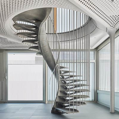 Skulpturale Betontreppe verbindet Stockwerke freitragend – ideal für lichtdurchflutete Räume