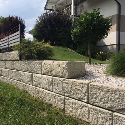 Gepflegte Hangabstützung mit Pflanzen und Kies – ideal für stilvolle Vorgartengestaltung