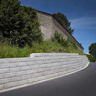 Lange Stützmauer sichert steilen Hang direkt an der Straße