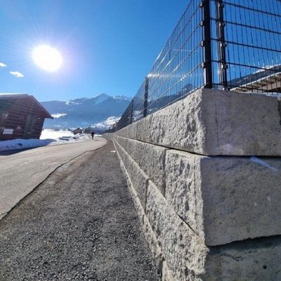 Massive Betonmauer mit Zaun sichert den Weg am Hang – stabile Lösung im Alpenraum